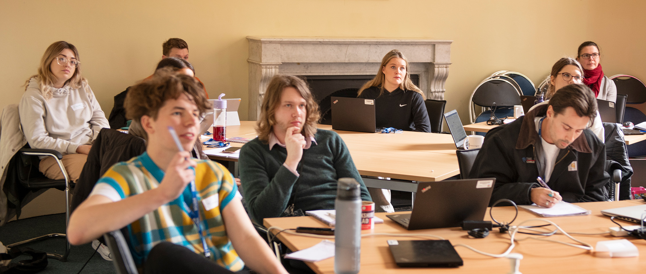 A group of apprentices sat at tables with laptops as they listen and learn.