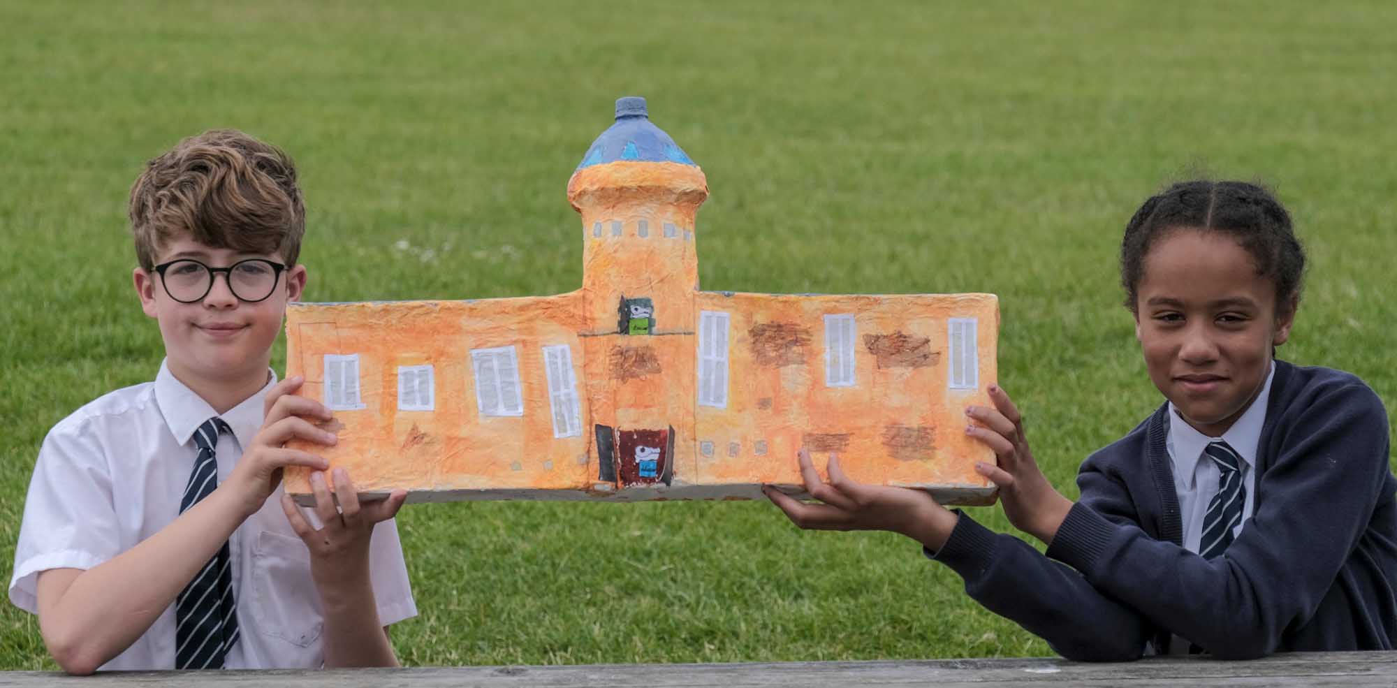 A boy and girl each holding one end of a papier-mâché  model they made of the outside of Scarborough's Rotunda Museum.