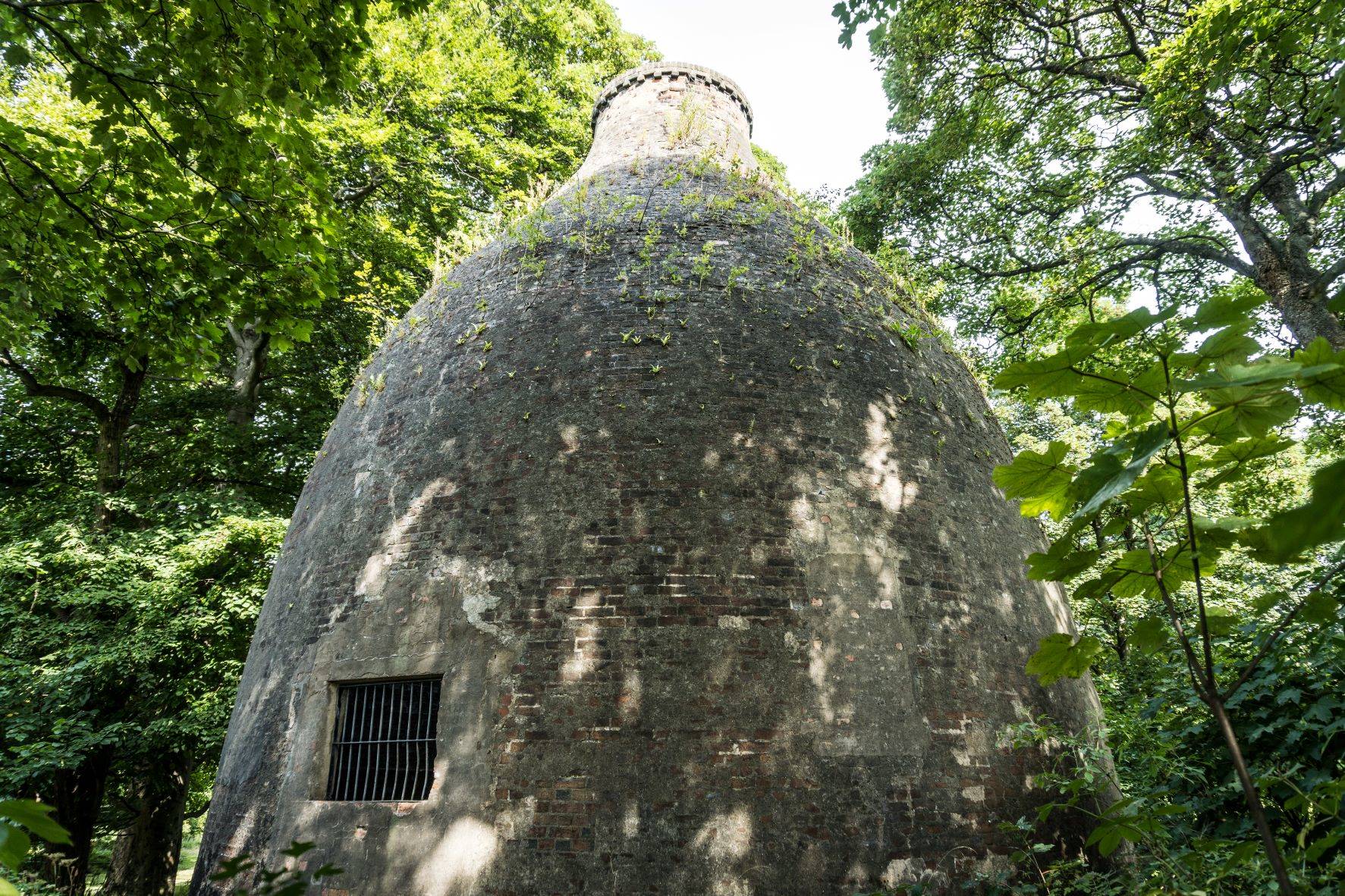 A bottle-shaped brick building surrounded by trees. 