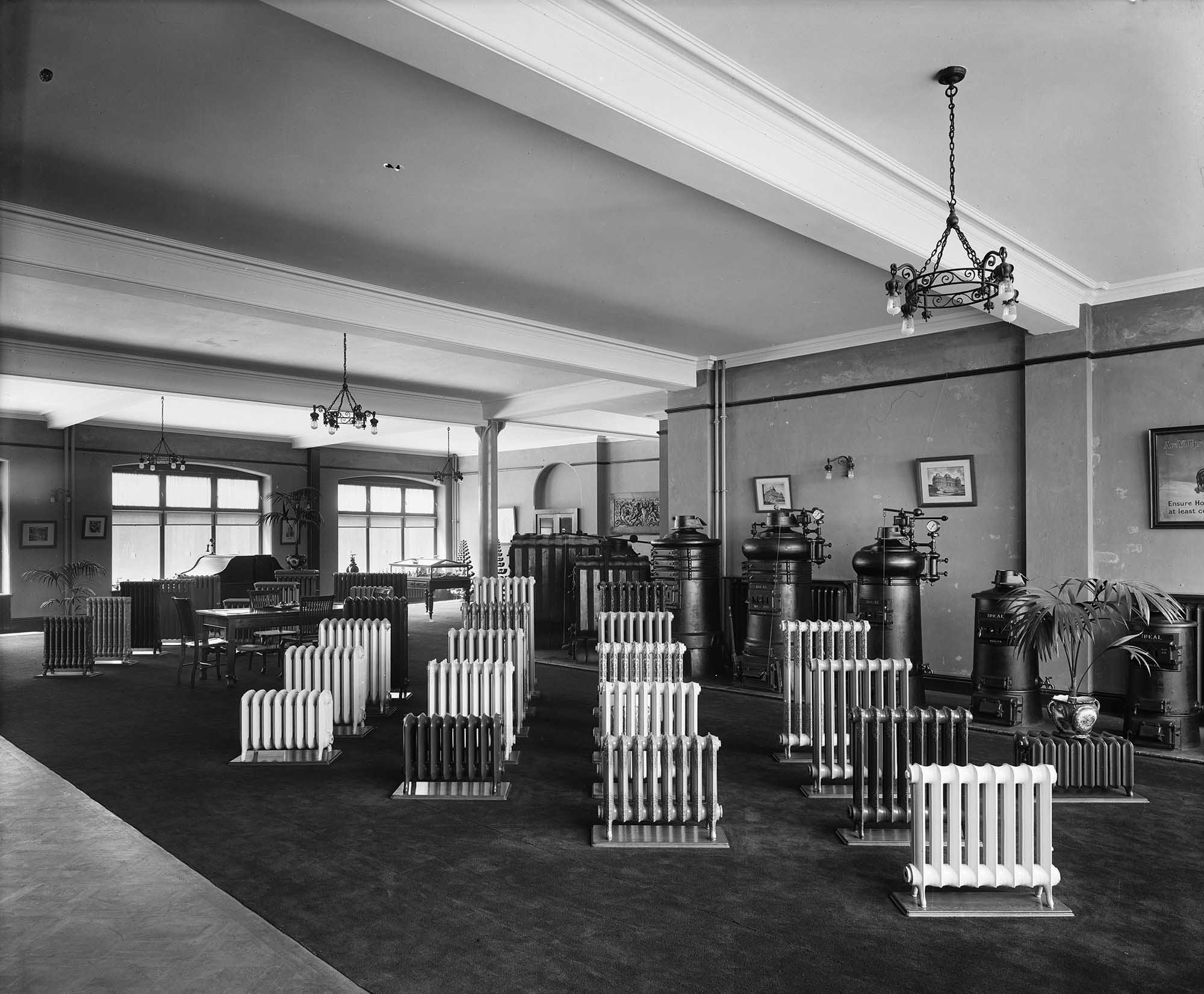black and white photo of a large showroom with numerous radiators on central display.