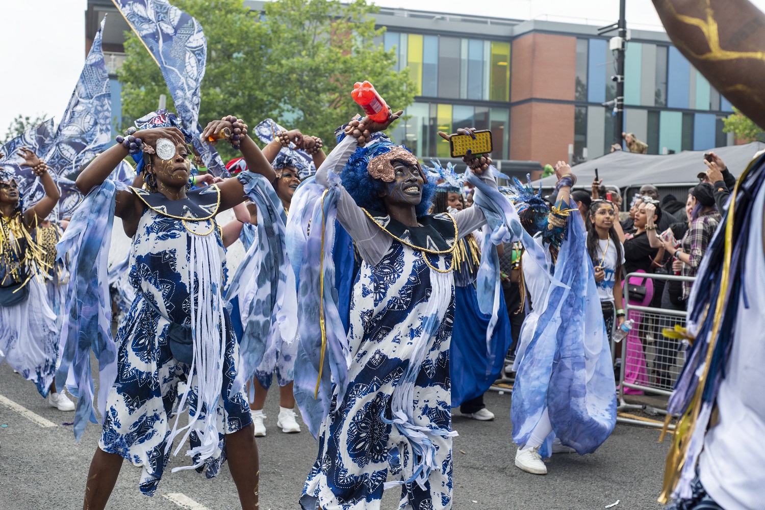 A group of carnival dancers in bright clothing, dancing along an urban street