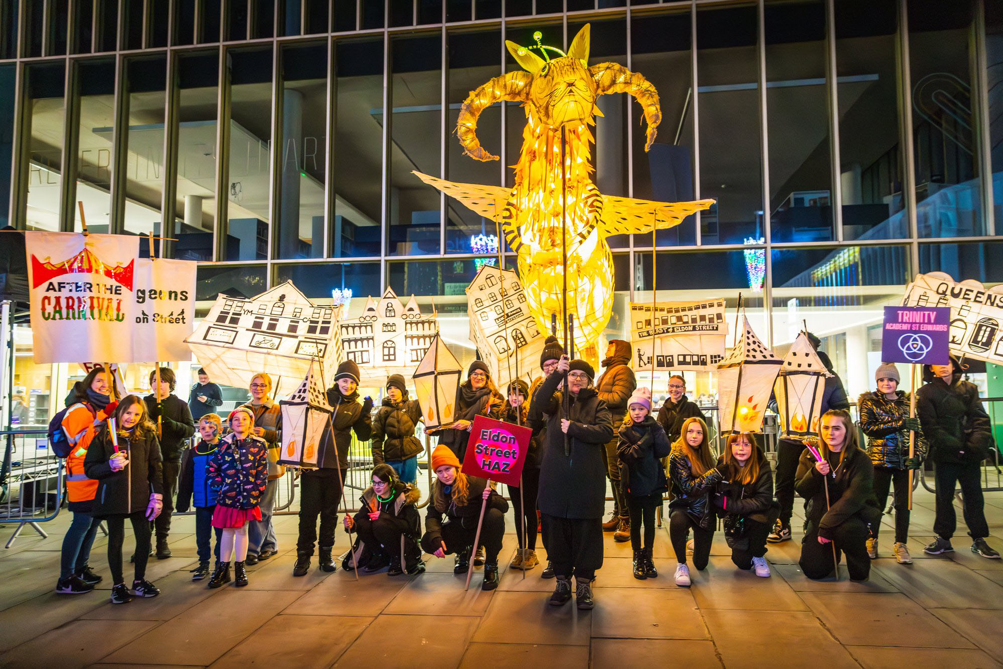 Light festival participants carrying lanterns line up for a group photo including a mix of adults and children.