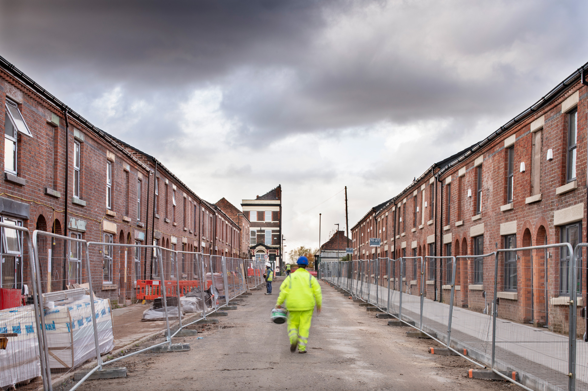 Street of terraced housing under building works with builders on site