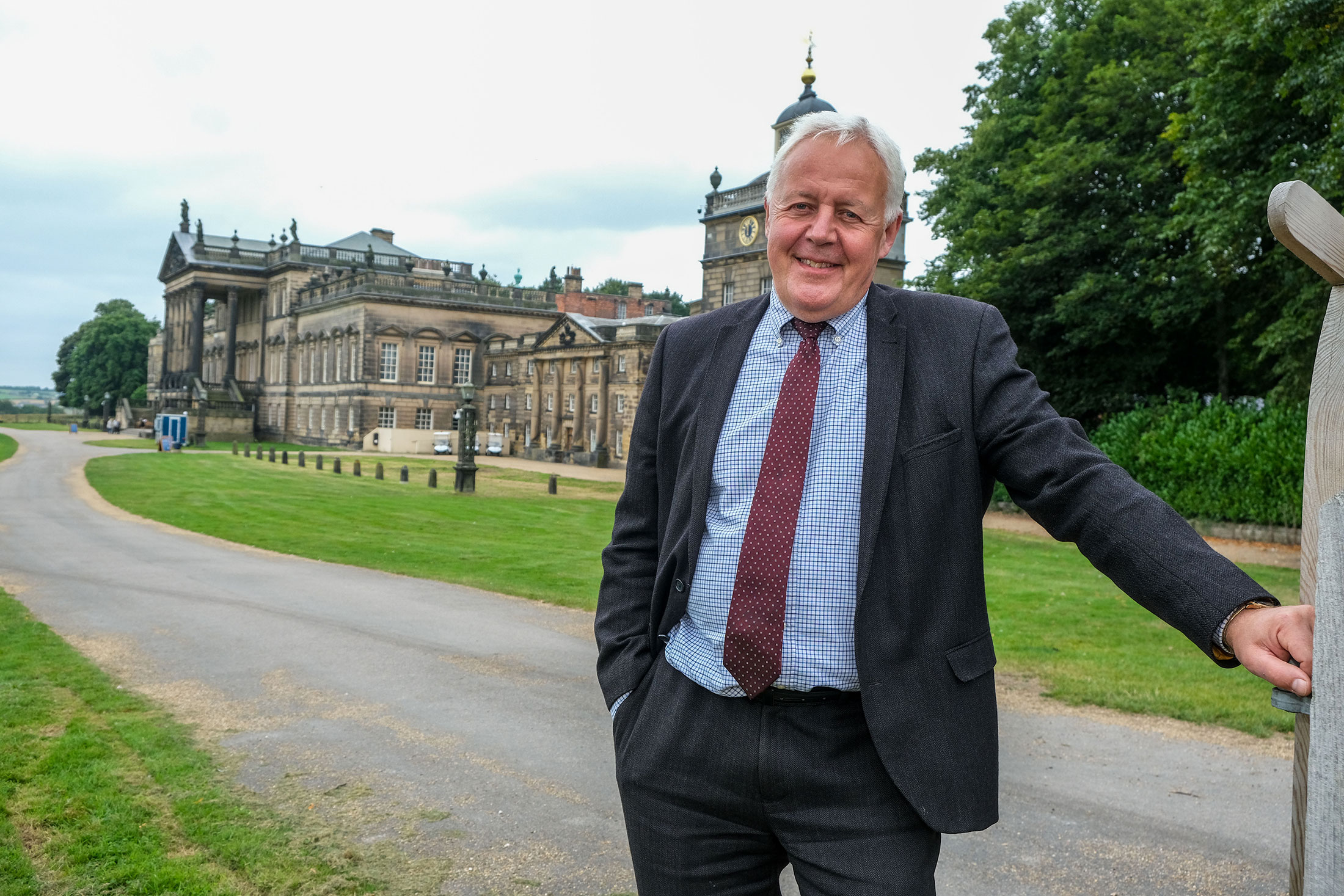 Duncan Wilson wearing a suit and tie and a warm smile standing in front of stately home Wentworth Woodhouse