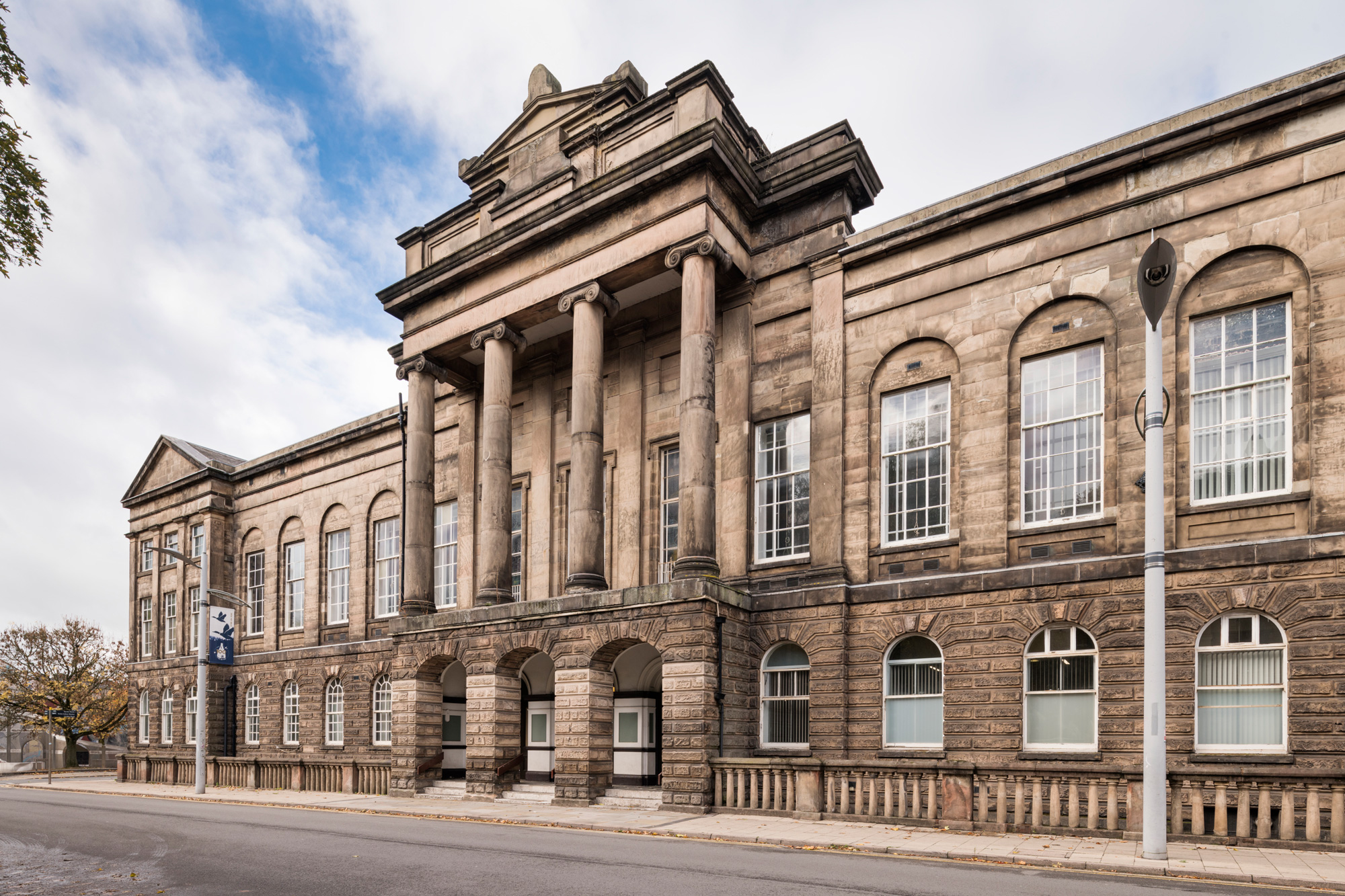 Sandstone town hall building with arched windows and grand portico featuring Ionic columns.