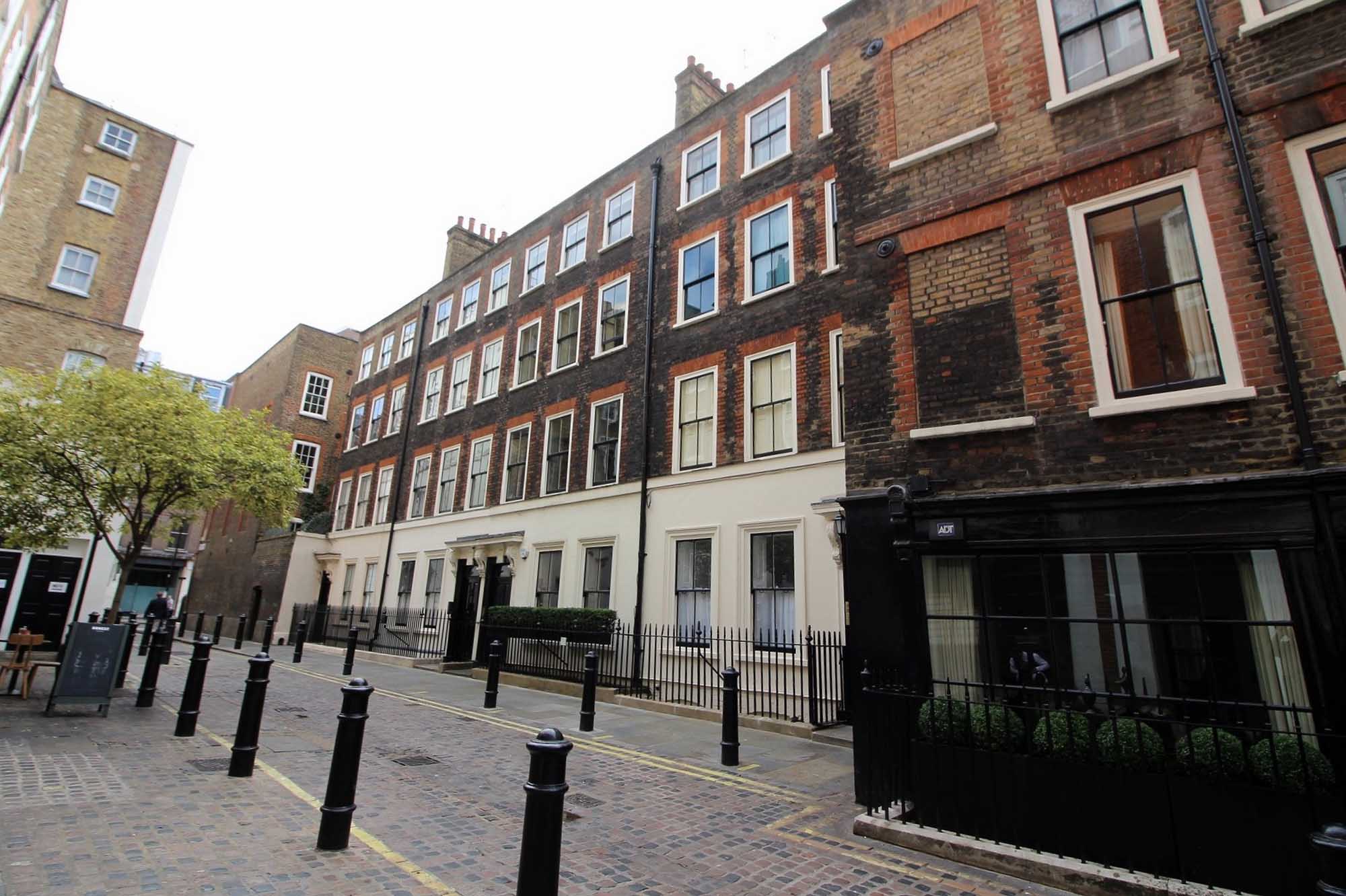 View of Georgian buildings with railings and bollards in front of them.