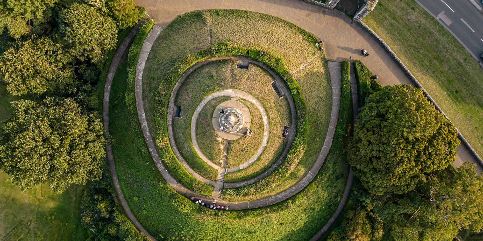 Birds-eye view of a grassy mound with circular pathways.
