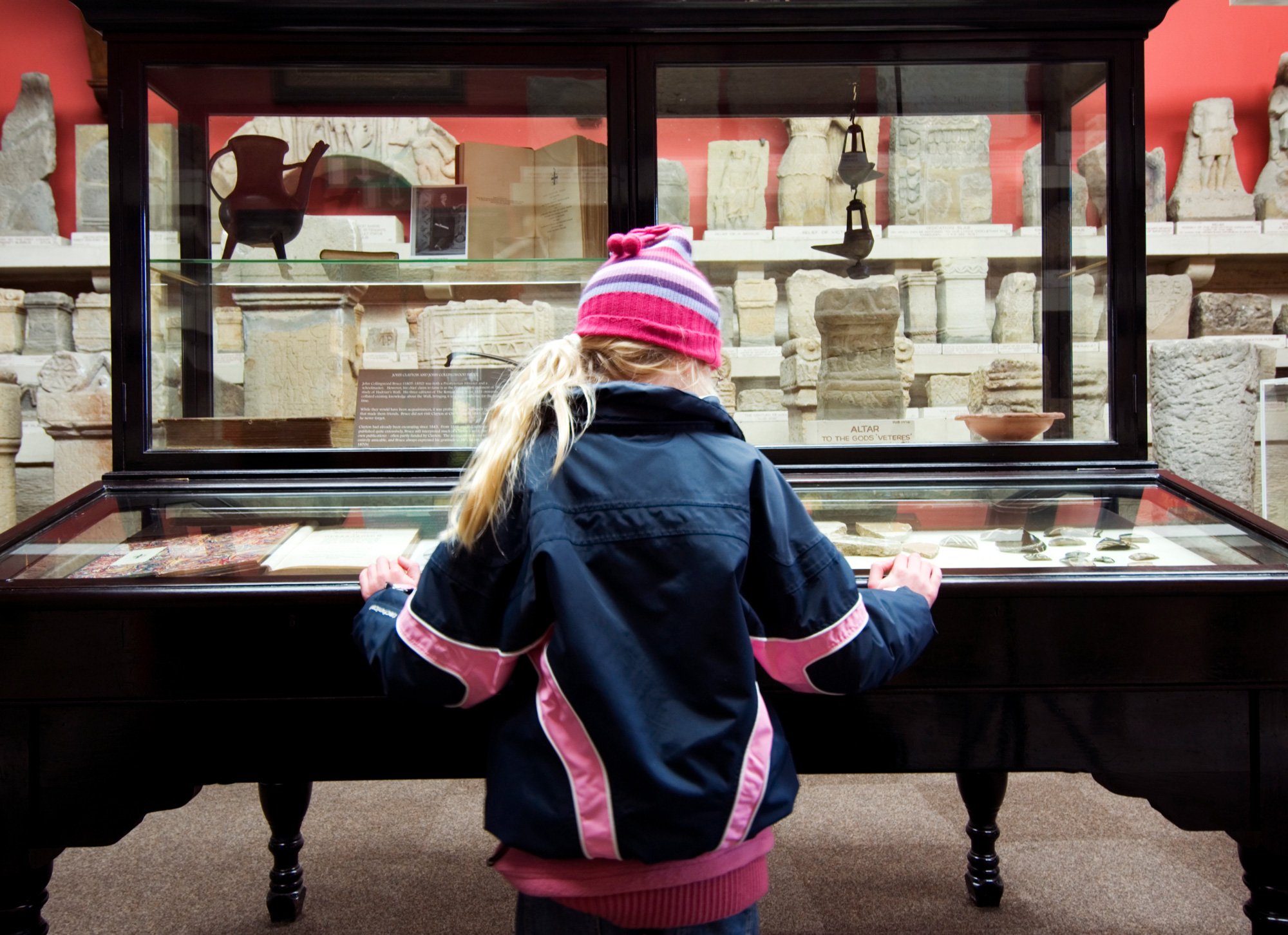 Interior view showing a young visitor examining display cases in a museum.